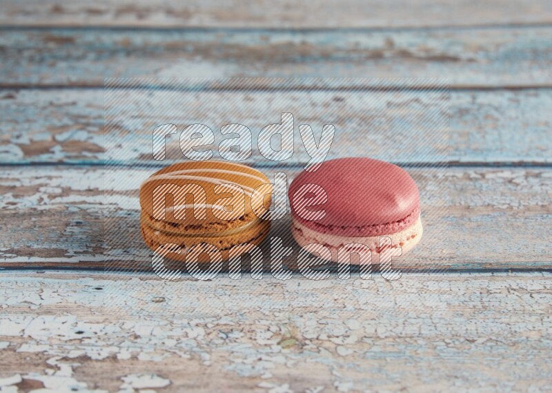 45º Shot of of two assorted Brown Irish Cream, and Pink Litchi Raspberry macarons on light blue background