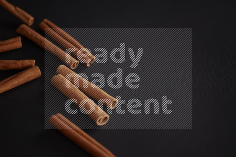 Cinnamon sticks stacked on black flooring