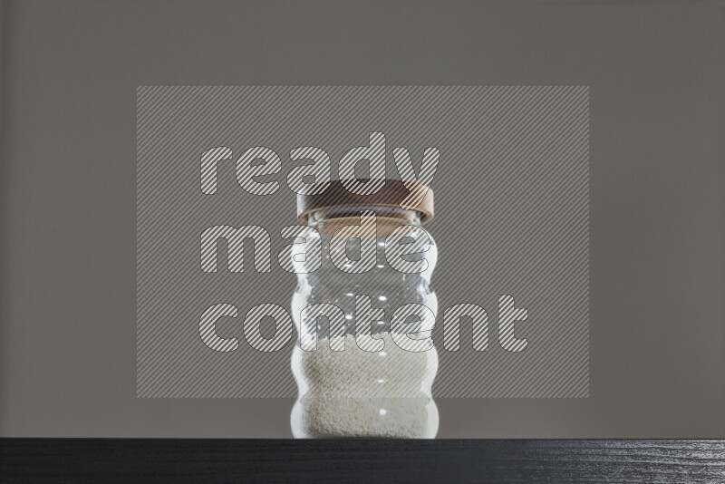 Desiccated coconut in a glass jar on black background