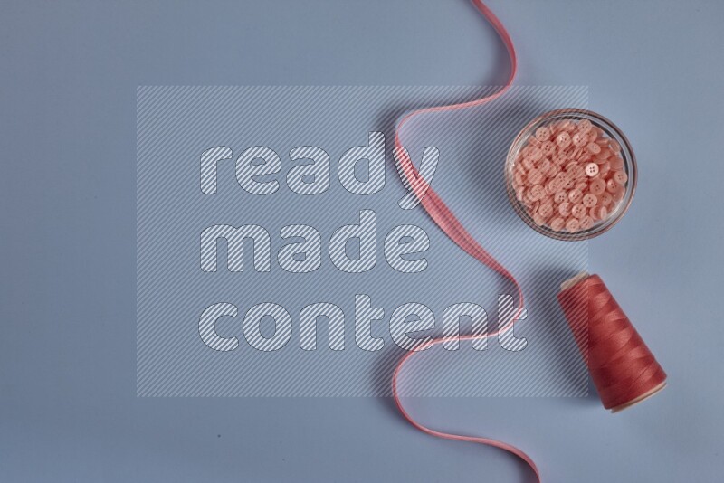 A pink collection of sewing and tailoring tools arranged on a blue background