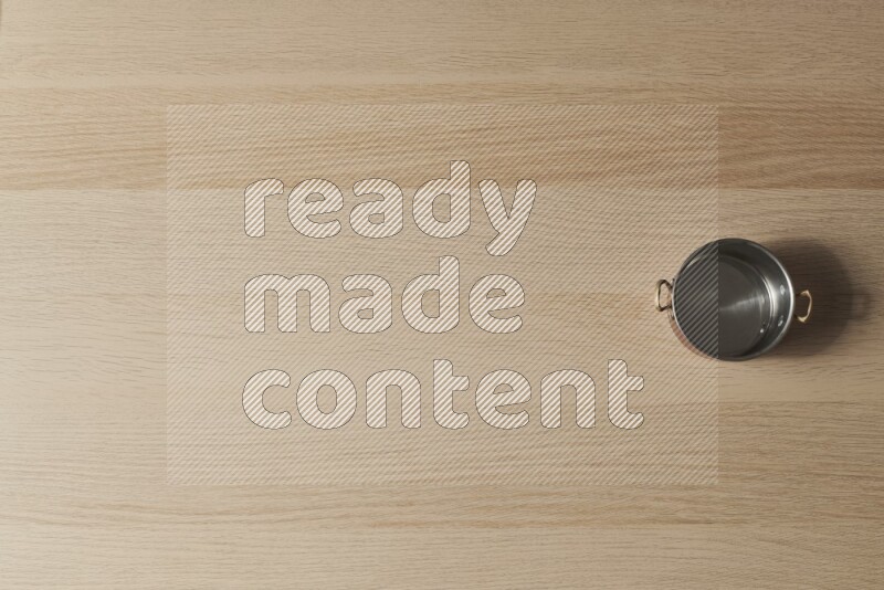 A small copper pot on light wooden background