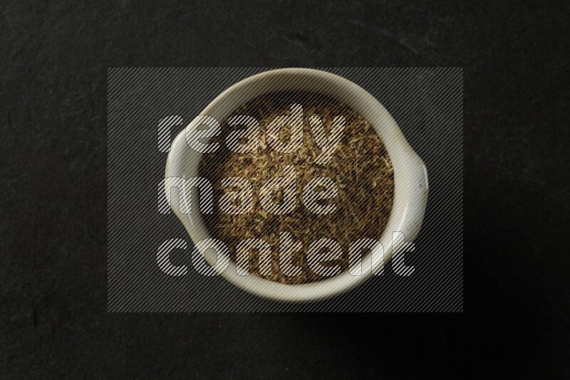 white ceramic round sauce bowl filled with herbs on grey textured countertop