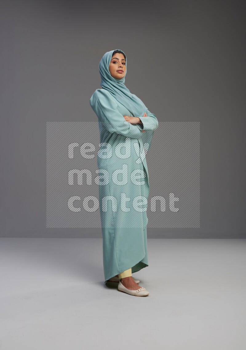 Saudi Woman wearing Abaya standing with crossed arms on Gray background