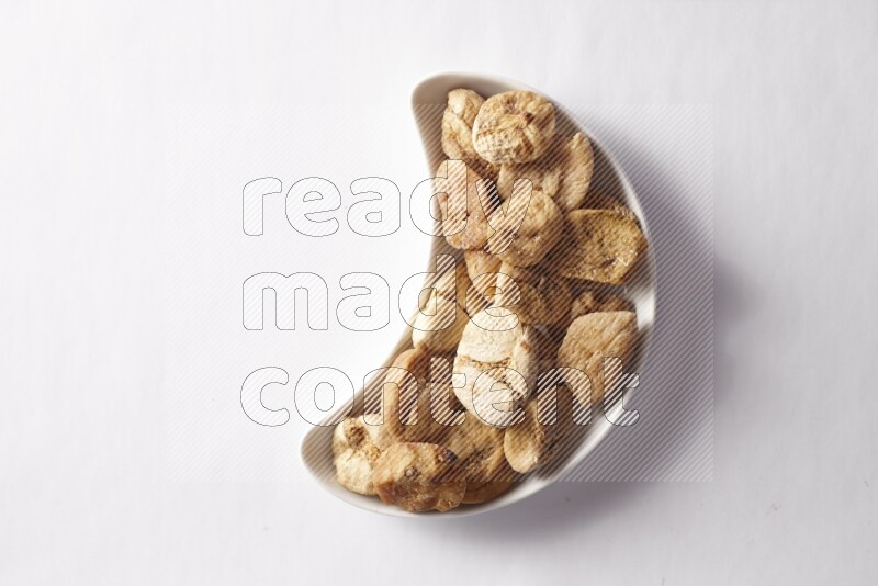 Dried figs in a crescent pottery plate on white background