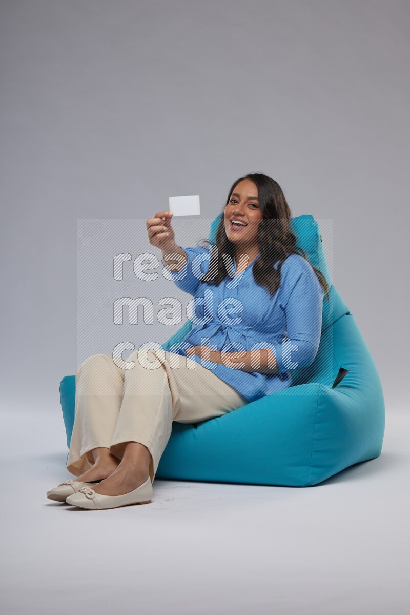 A woman sitting on a blue beanbag and holding ATM card