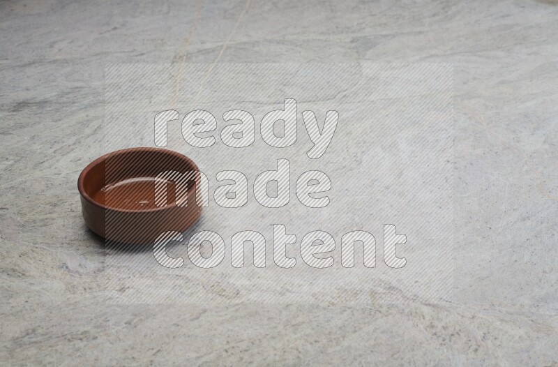 A brown pottery bowl on grey marble background