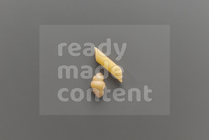 Snails pasta with other types of pasta on grey background