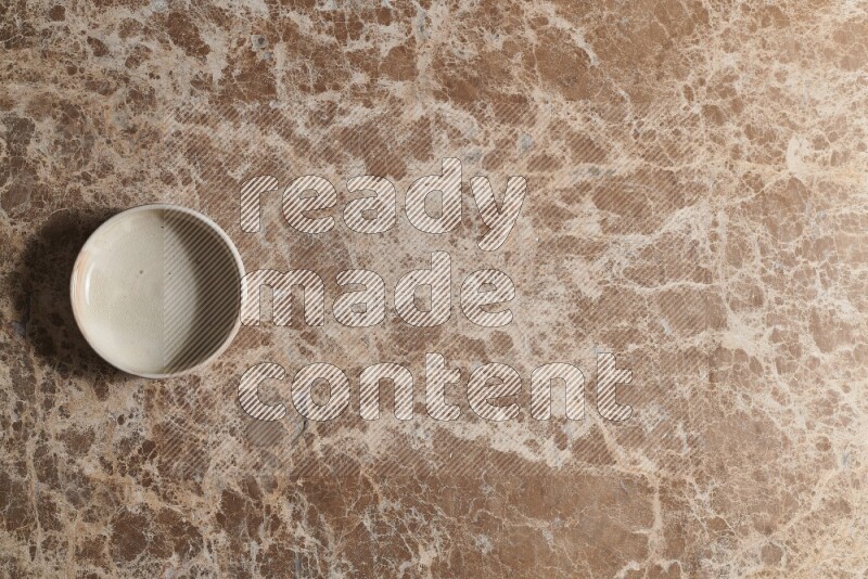 A white pottery bowl on beige marble background
