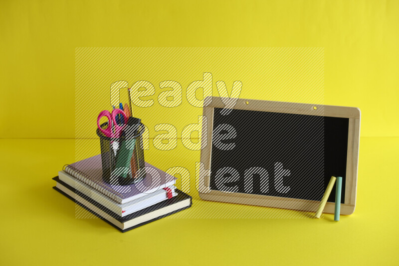 A blackboard with different school supplies on yellow background