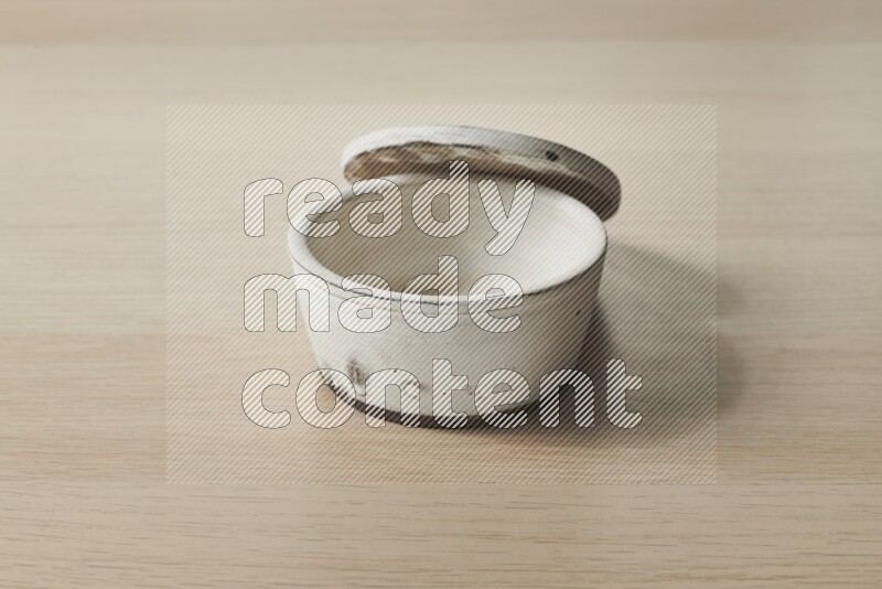 A white pottery bowl on light wooden background