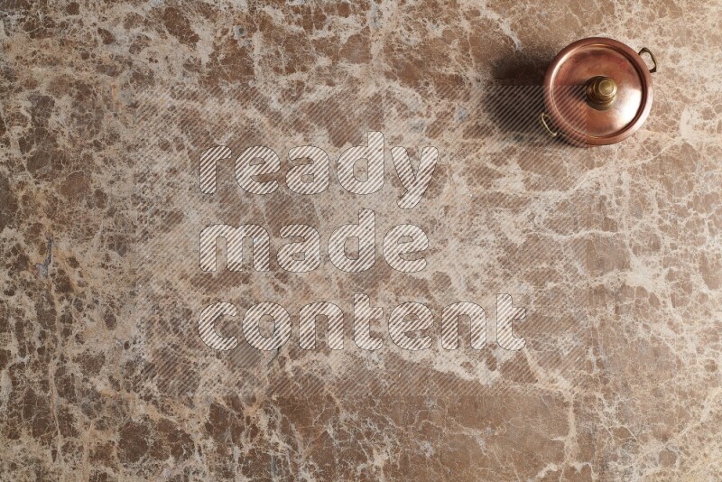 A small copper pot on beige marble background