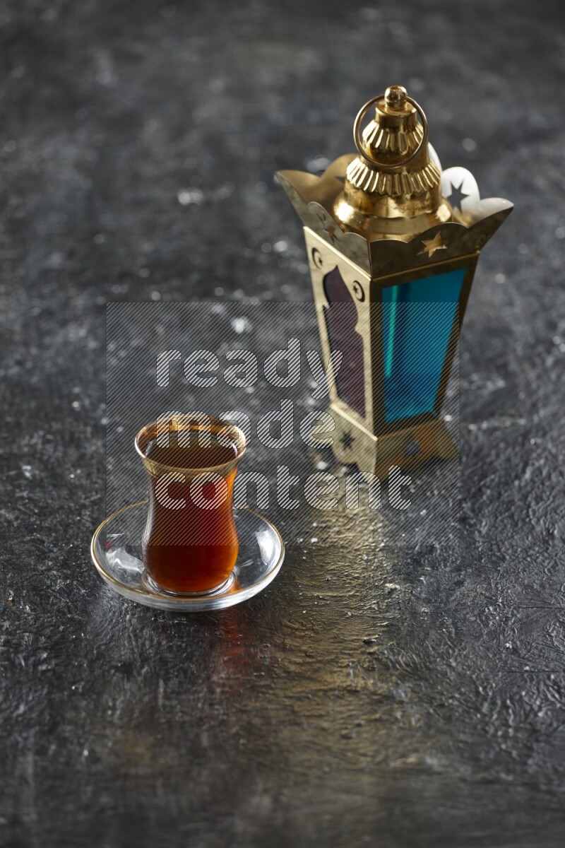 A golden lantern with different drinks, dates, nuts, prayer beads and quran on textured black background