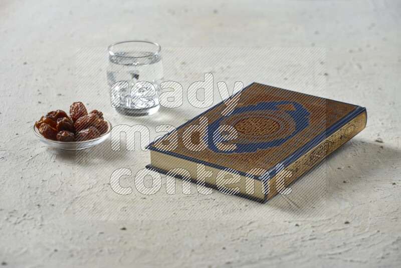 Quran with dates, prayer beads and different drinks all placed on textured white background