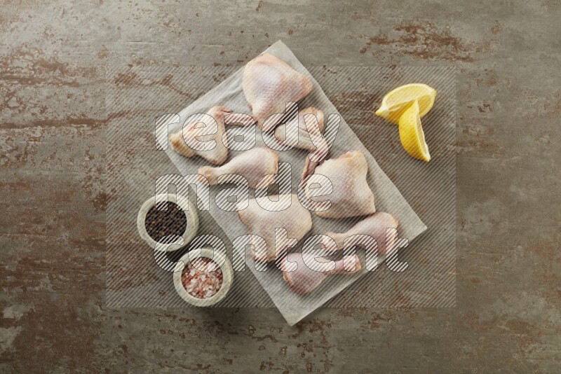 Mixed fresh chicken pieces on a parchment paper direct on a textured rustic background