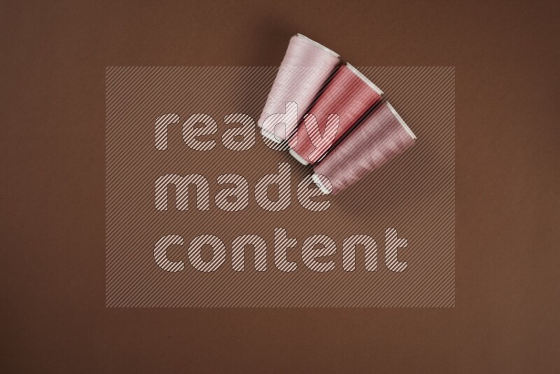 A pink collection of sewing and tailoring tools arranged on a brown background