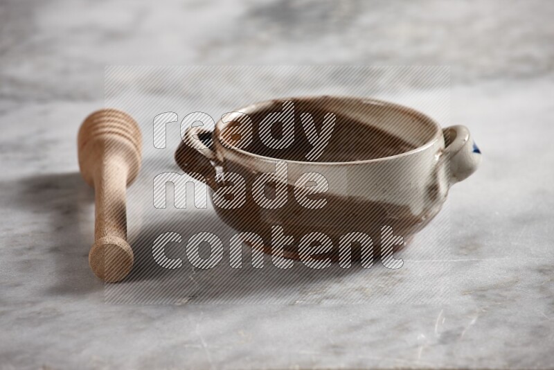 Multicolored pottery bowl with wooden honey dipper on the side on grey marble background