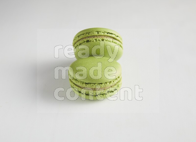 45º Shot of two Green Pistachio macarons on white background