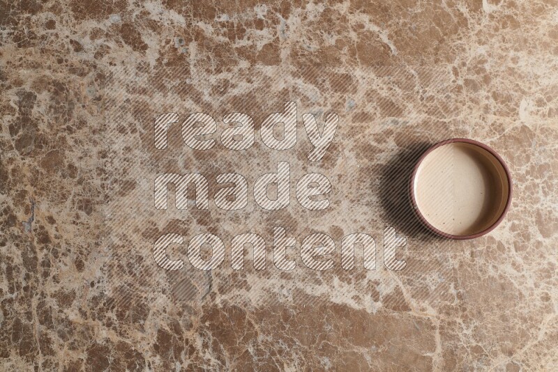 A beige pottery oven plate on beige marble background