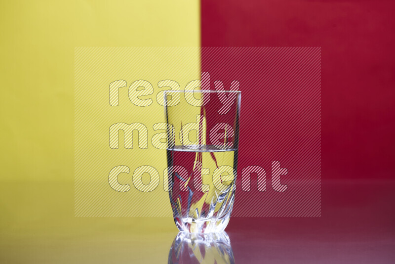 The image features a clear glassware filled with water, set against yellow and red background