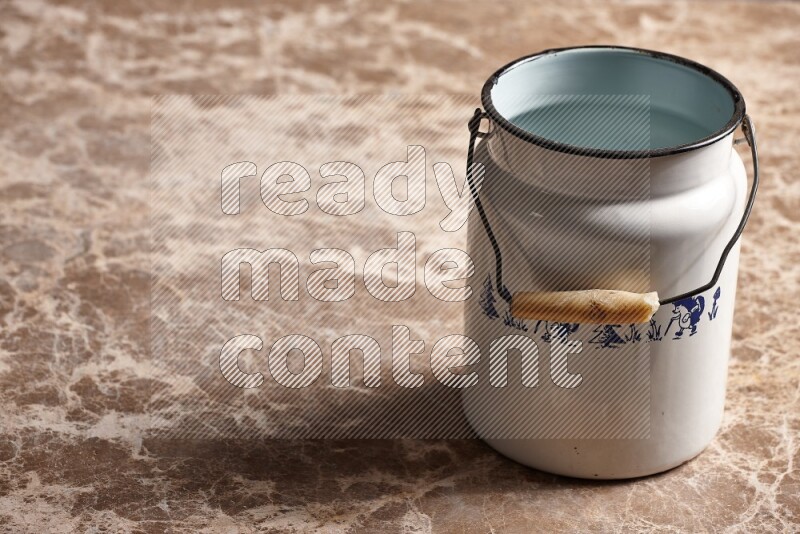A vintage milk can on beige marble background