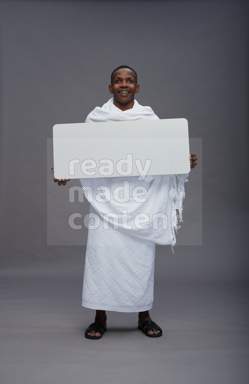 A man wearing Ehram Standing holding board sign on gray background