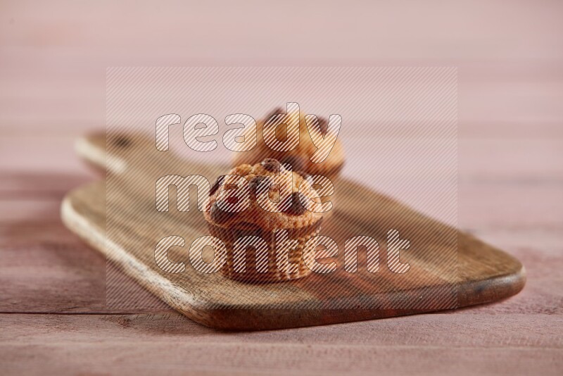 Vanilla mini cupcake topped with chocolate chips on a wooden board