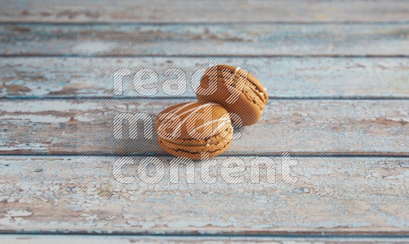 45º Shot of two Brown Irish Cream macarons on a  light blue wooden background
