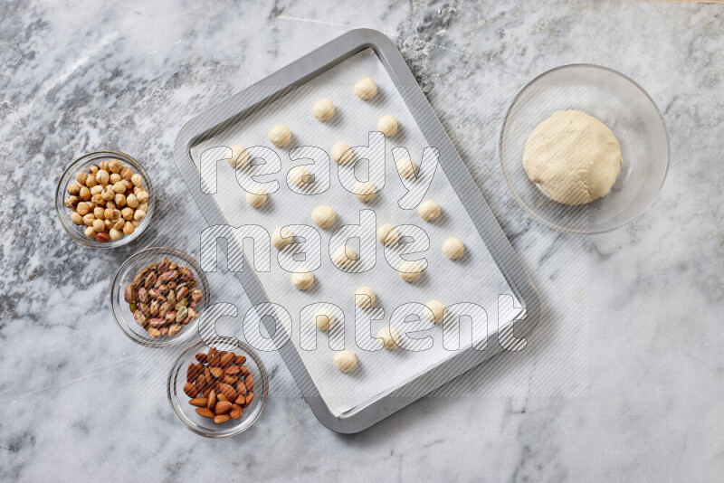 Ghoriba step by step with its ingredient, flour, powdered sugar, ghee and nuts on grey marble background