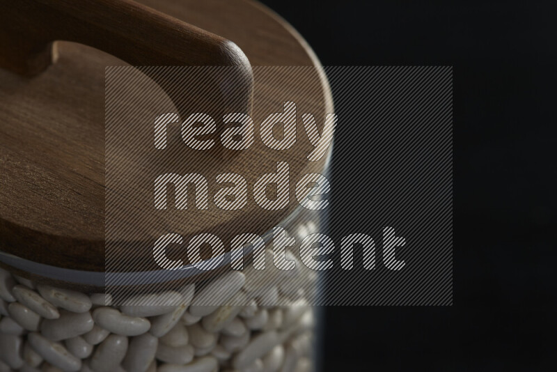 White beans in a glass jar on black background