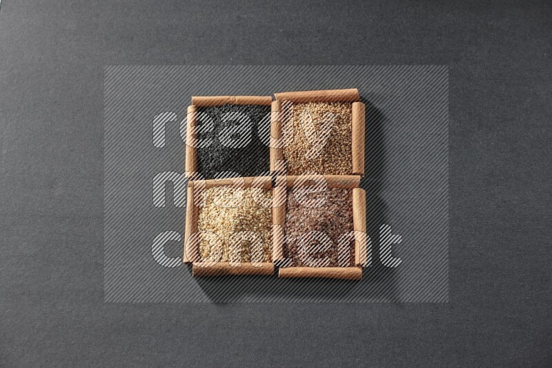 4 squares of cinnamon sticks full of black seeds, sesame, flaxseeds and mustard seeds on black flooring