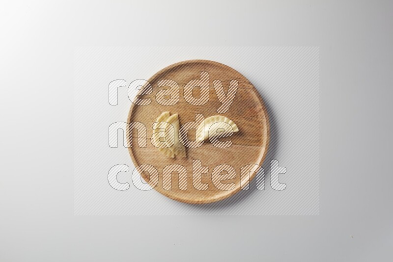 Three Sambosas on a wooden round plate on a white background
