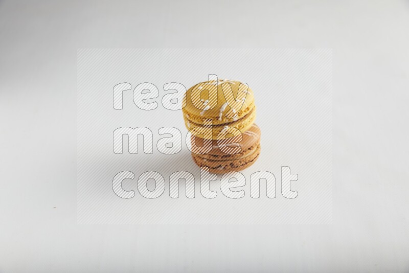 45º Shot of of two assorted Brown Irish Cream, and Yellow Piña Colada macarons on white background