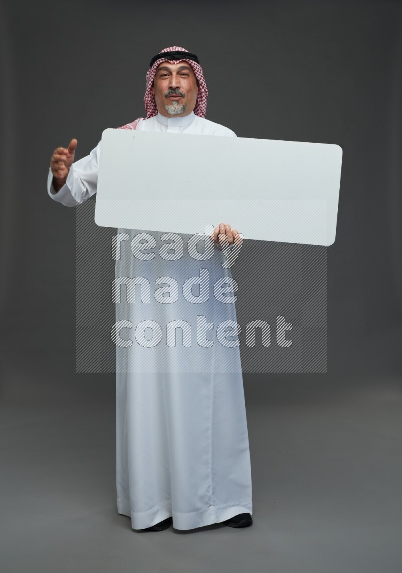Saudi man with shomag Standing holding social media sing on gray background