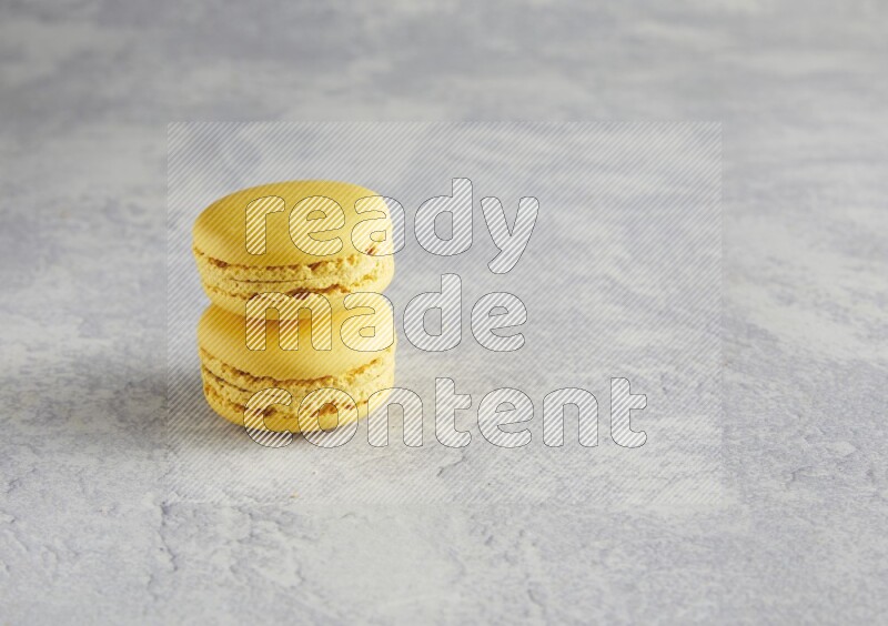 45º Shot of two Yellow Lemon macarons  on white  marble background
