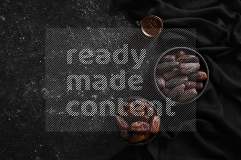 Dates in pottery bowls with coffee in a dark setup