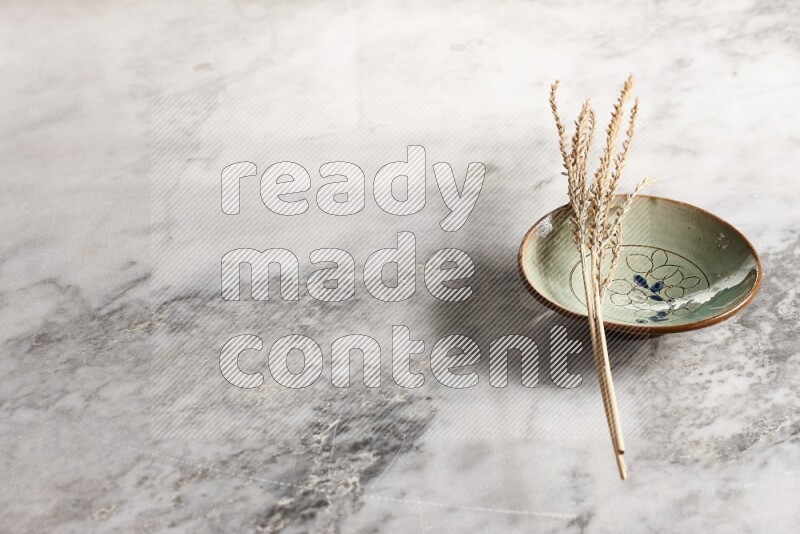 Wheat stalks on decorative pottery plate on grey marble background
