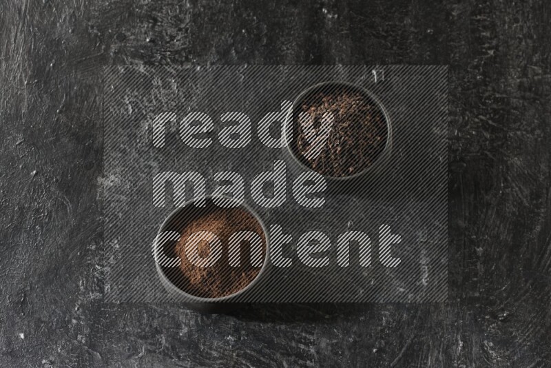 وعاءين من الفخار الأسود أحدهما ممتلئي بحبوب القرنفل والآخر ممتلئ ببودرة القرنفل على خلفية سوداء