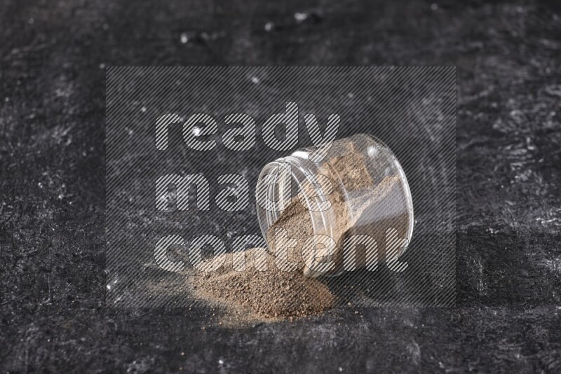 بودرة الفلفل الأسود في وعاء زجاجي مقلوب علي خلفية سوداء