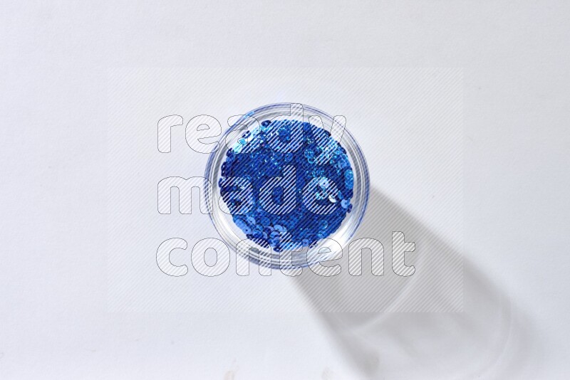 Colored flat sequins in a glass bowl on grey background