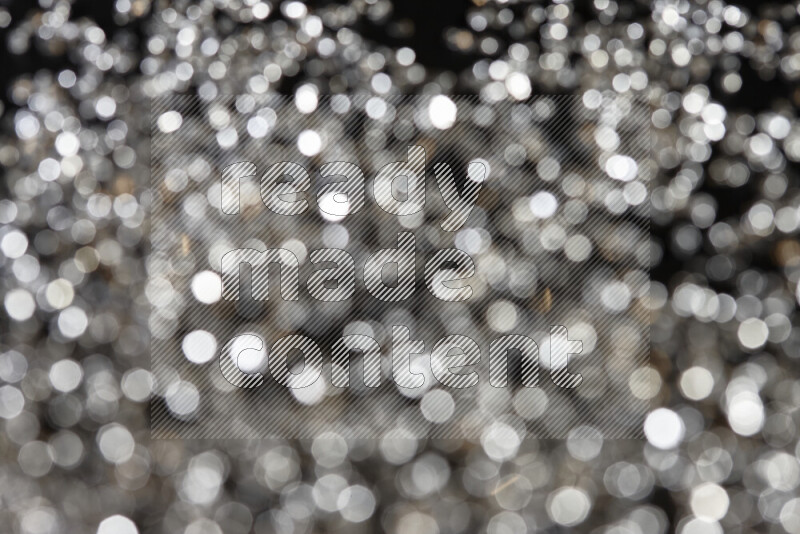 Silver shimmering fragments of glass scattered on a black background