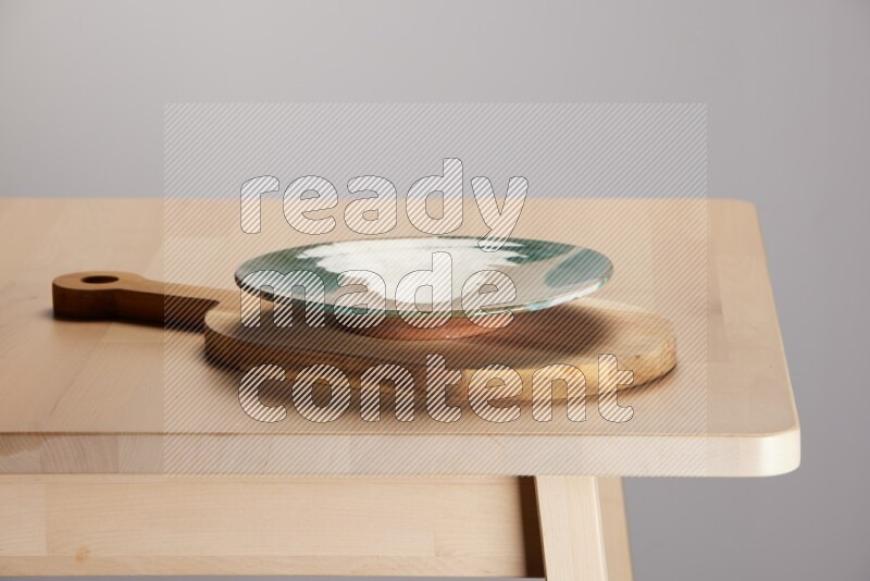 multi colored plate placed on a  wooden oval cutting board on the edge of wooden table