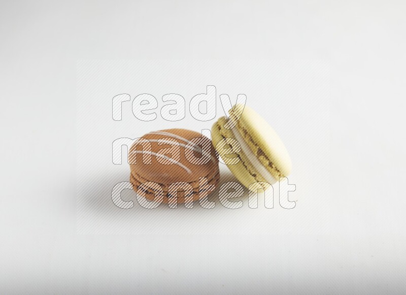 45º Shot of of two assorted Brown Irish Cream, and Yellow Lime macarons on white background