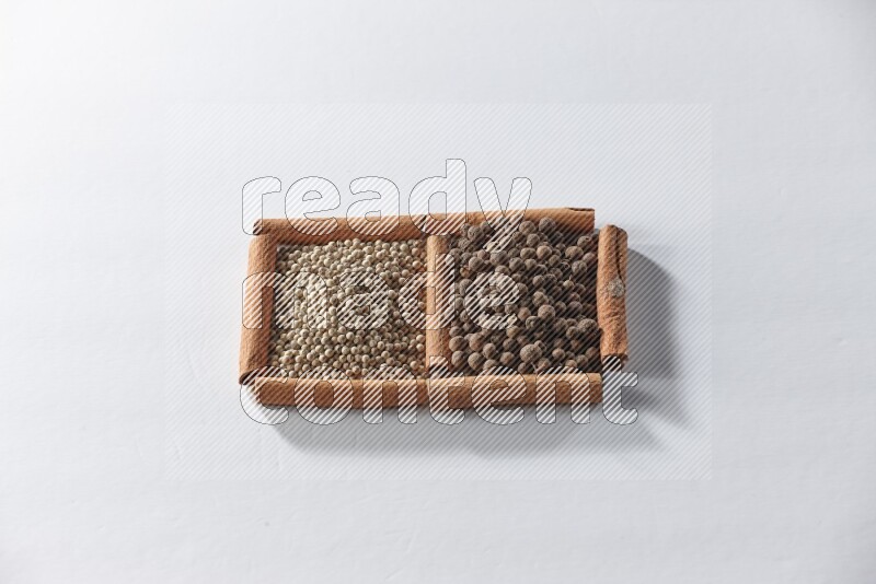 2 squares of cinnamon sticks full of white pepper and allspice on white flooring