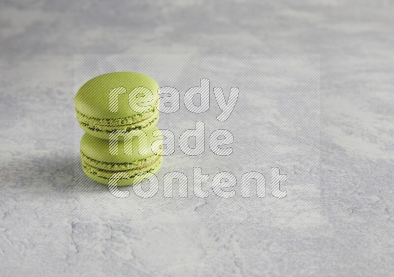 45º Shot of two Green Pistachio macarons  on white  marble background
