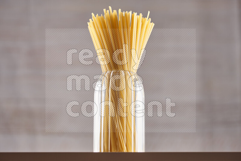 Raw pasta in glass jars on beige background