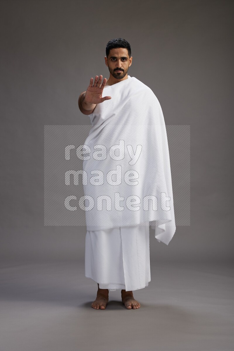 A man wearing Ehram Standing Interacting with the camera on gray background