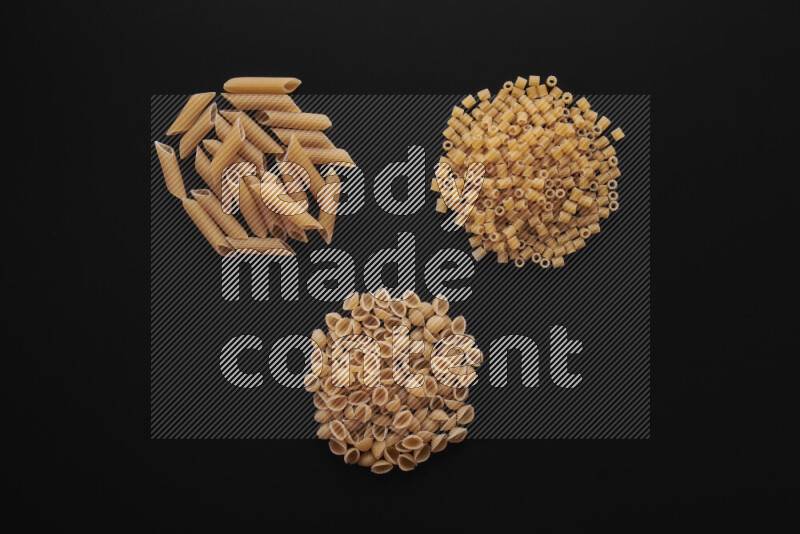 Different pasta types in bunches on black background