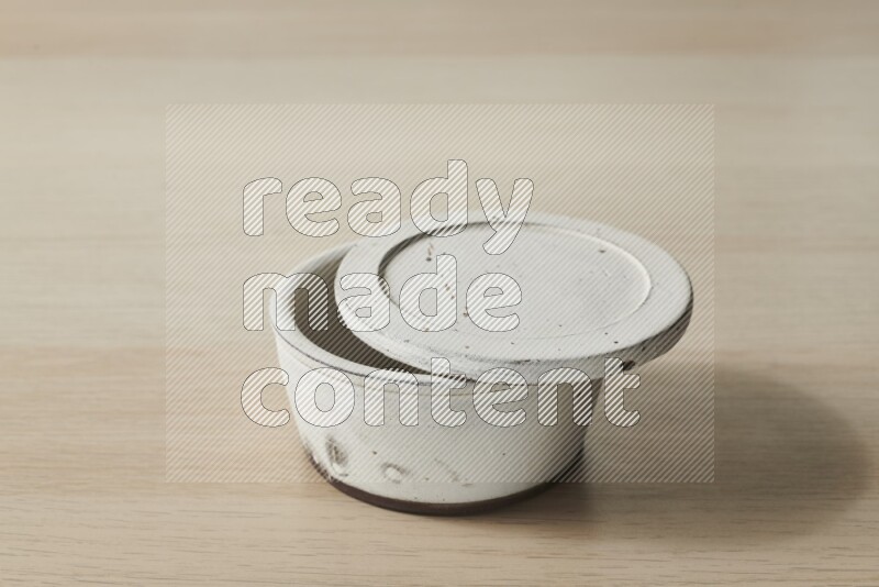 A white pottery bowl on light wooden background