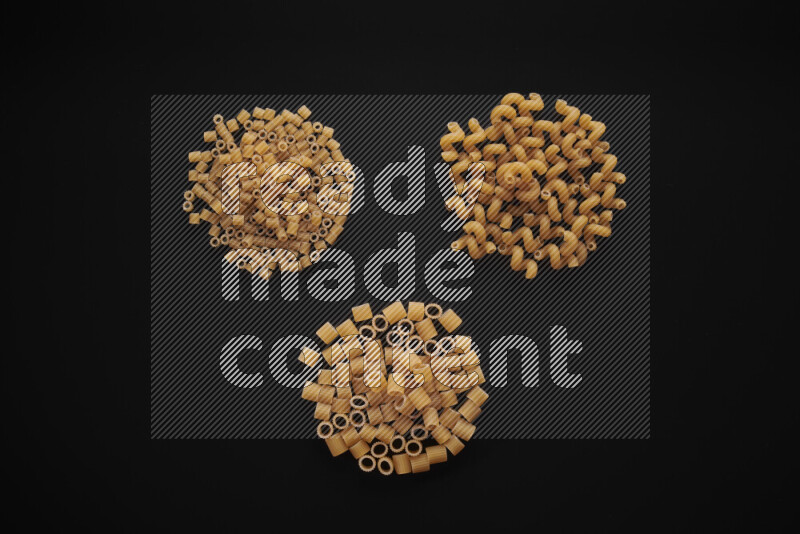 Different pasta types in bunches on black background