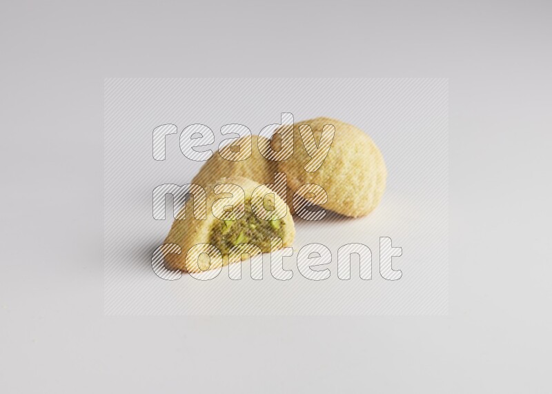 Three Pieces of Maamoul filled with pistachio paste  one of them is cut direct on white background